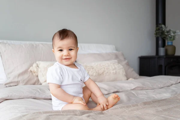 笑顔の9ヶ月の少女の肖像画ベッドの上に座って ロイヤリティフリーのストック画像