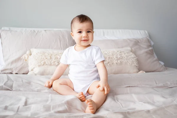9ヶ月の少女の肖像画で 茶色の目がベッドの上に座っている ロイヤリティフリーのストック画像