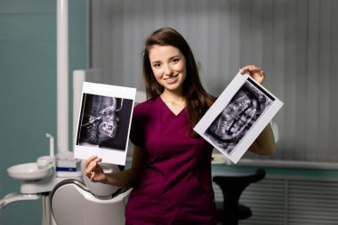 Diş muayenehanesinde ellerinde diş taramaları olan güzel bir kadın doktor.