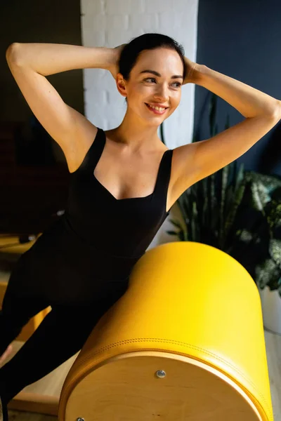 Femme sportive faisant pilates tonifiant exercice sur yoga pilates échelle baril machine d'entraînement. Exercice portant des vêtements de sport, gymnase. — Photo