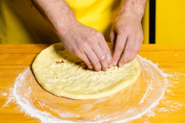 Genç ve çekici aşçı sarı arka planda Hint naanı pişiriyor.