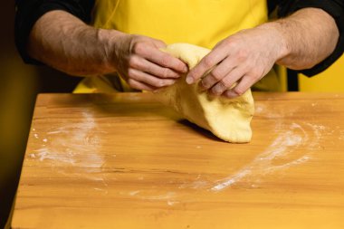 Genç ve çekici aşçı sarı arka planda Hint naanı pişiriyor.