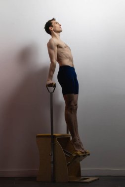 Pilates reformer chair man fitness yoga gym exercise. Correction of musculoskeletal system, beautiful body.