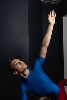 Sporty man doing exercises on pilates reformer training machine. Working out wearing sportswear, gym.