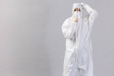 Coronavirus zamanlarında hastanede maske ve eldiven takan yorgun doktor, akıllı telefonunu kontrol ediyor..