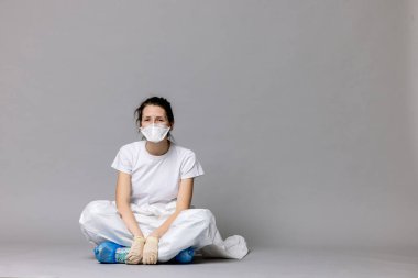  Yerde koruyucu giysili, yorgun bir kadın doktor. Salgın bir covid-19 'a karşı verilen mücadelede yorgun düşmüş.