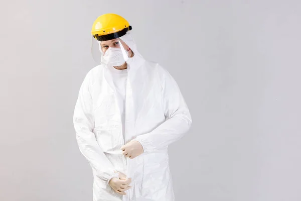 Médico cansado usando máscara e luvas no hospital em tempos de coronavírus, verificando seu smartphone . — Fotografia de Stock