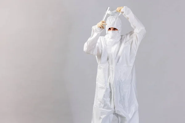 Medico stanco indossando maschera e guanti in ospedale in tempi coronavirus, controllando il suo smartphone . Fotografia Stock