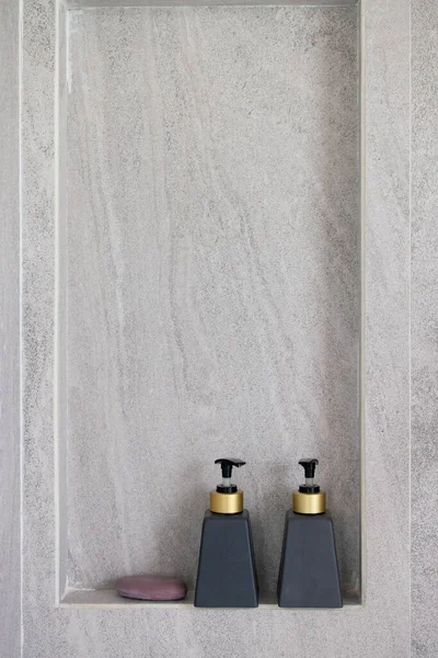 Due bottiglie bianche di condizionatore, gel doccia su ripiano in bagno moderno con parete strutturata Immagini Stock Royalty Free