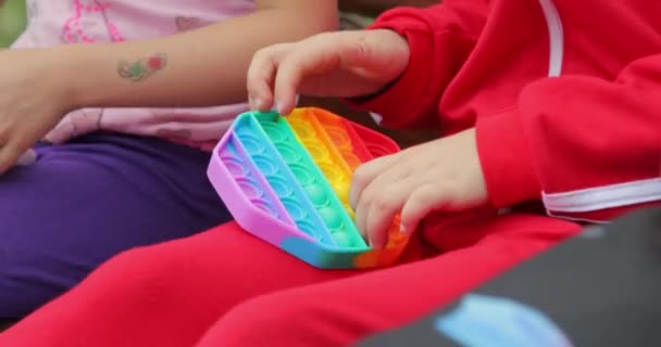 子供の女の子の手は人気のシリコーン抗ストレスおもちゃで遊んでそれをポップし、単純なディンプル。閉鎖 — ストック動画