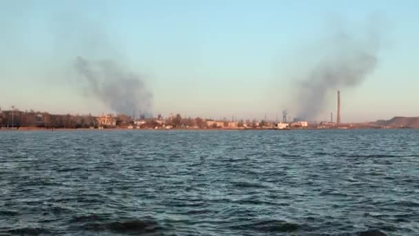View from the sea to the large foundry, Azovstal, with smoking pipes. Ecological problem of air and environment pollution in large cities. Ukrainian city of Mariupol. — ストック動画