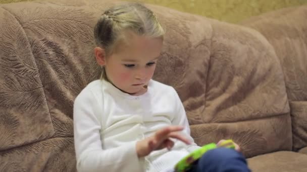 Jolie fille préscolaire jouant à la mode populaire jeu de société silicone fossettes simples et des jouets pop-it tout en étant assis sur le canapé dans la chambre. Le développement de la motricité. Plan moyen — Video