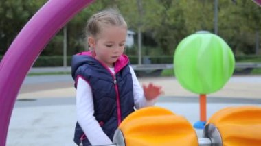 Gündelik giysiler içinde küçük şirin bir kız yenilikçi bir çocuk parkında büyük bir turuncu top çeviriyor. Modern çocuk gelişimi. Orta boy. Orta boy..