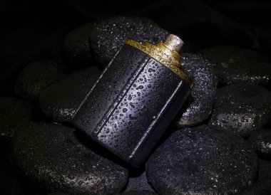 Closeup black perfume bottle closeup on stones