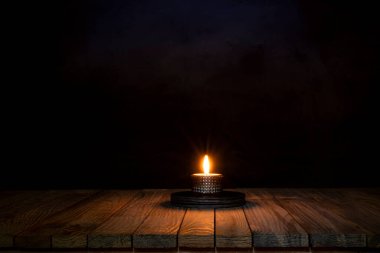 Candle light spreading on wooden table surface.