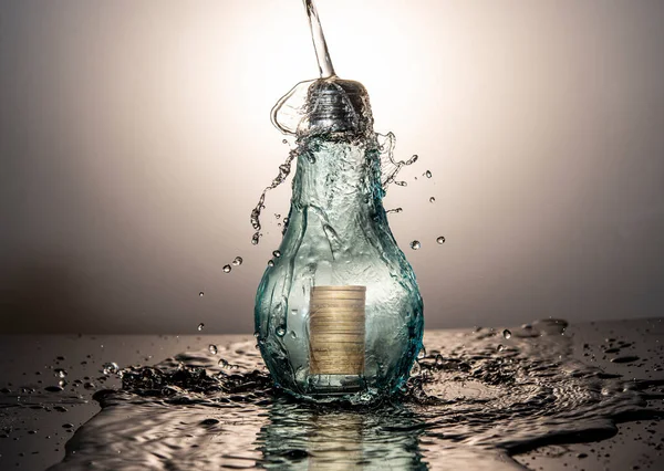用灯泡和硬币外的水来保护你的投资理念 — 图库照片