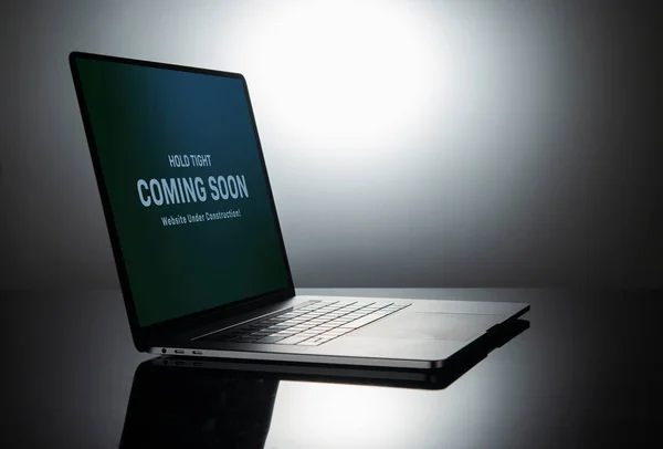 Coming soon banner on laptop screen showing website under construction sign.