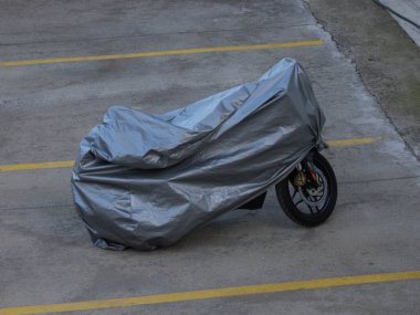 Otoparkta siyah plastik çantayla kaplı bisiklet.