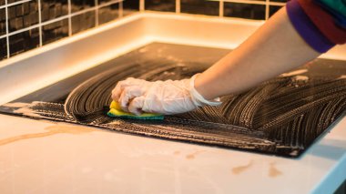 Mutfak lavabosunu süngerle temizleyen kadın.