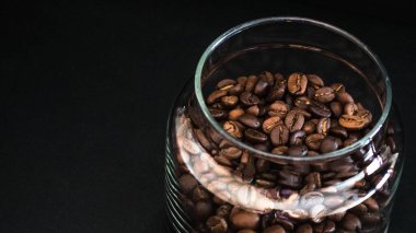 Cam kavanozda kahve çekirdekleri, cam bankada kahve çekirdekleri, siyah arka planda kahve çekirdekleri. 