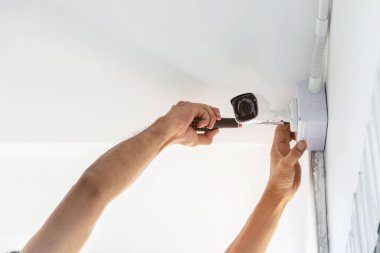 Güvenlik amacıyla evin duvarlarına kamera yerleştirmek için tornavida kullanan teknisyenler..