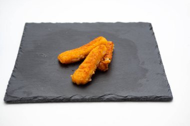 Beyaz arka planda izole edilmiş dökme demir tabakta balık çubukları.