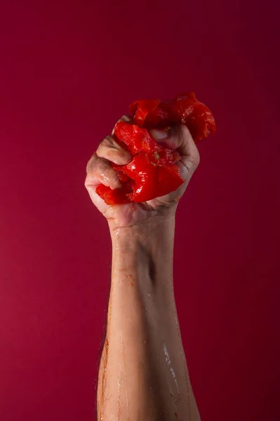 Pomodoro Succoso Schiacciato Mano Maschile Sfondo Rosso — Foto Stock