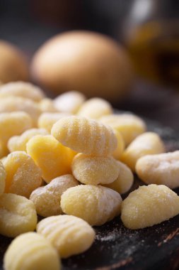 Koyu ahşap arka planda ıspanaklı çiğ İtalyan gnocchi. Bunlar hamur köftesi, genellikle oval, buğday unundan yapılmış, yumurtalı.