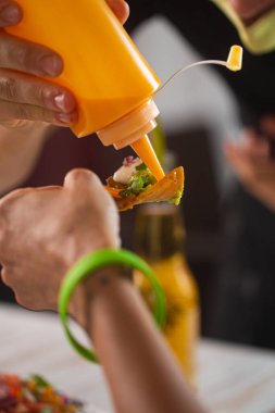 Restoran ziyaretçileri Meksika usulü atıştırmalık cipslere sıcak sosis döküyorlar.