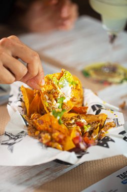 Restoran ziyaretçisi Meksika usulü Meksika usulü nacho, guacamole ve pico de gallo sosu yiyor.