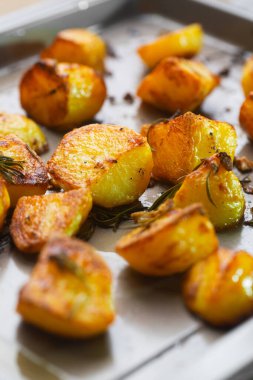Roasted potatoes on the baking sheet with garlic and rosemary , selective focus. Baked potatoes are the most popular food at Christmas