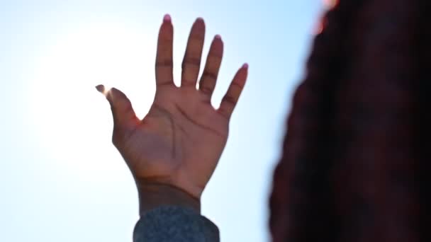 Zwart meisje speelt met de stralen van de zon met haar hand — Stockvideo