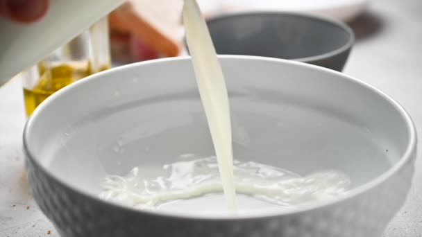 Mleko wlewa się do pustej miski w kuchni. — Wideo stockowe
