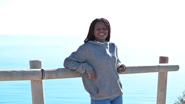 Mujer negra de pie sobre el fondo del mar y sonriendo — Vídeos de Stock