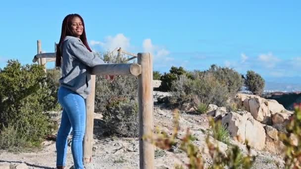 Fiatal fekete nő marad ellen ég és mosolyog széles körben — Stock videók