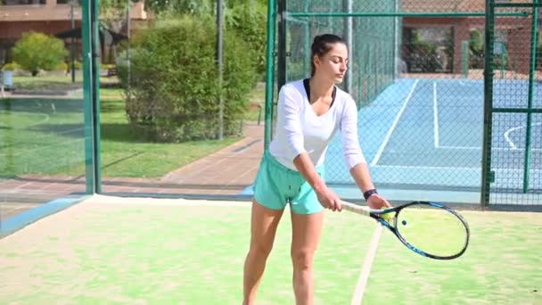 Mujer joven con el pelo largo juega tenis en el campo — Vídeos de Stock