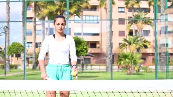 Chica hace malabares con una pelota de tenis con una raqueta — Vídeo de stock