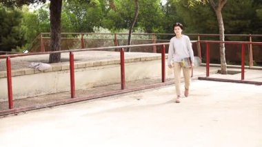 Genç kız kaykay tutuyor ve kaykay parkına gidiyor.