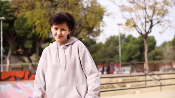 Adolescente chica montando monopatín en skatepark vacío y sonriendo — Vídeo de stock