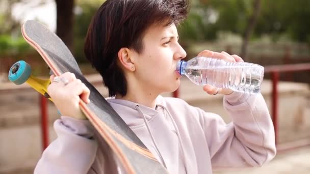 Skateboarder adolescente beber agua de la botella — Vídeos de Stock