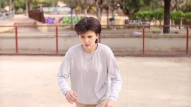 Boş bir kaykay parkında kaykay süren ikili olmayan bir genç.