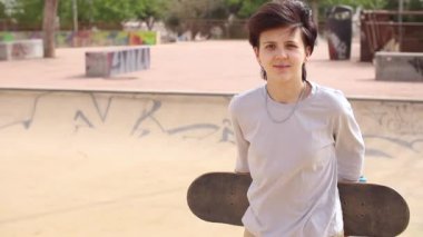 Genç kız kaykay tutuyor ve kaykay parkına gidiyor.