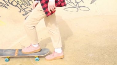 Genç kız kaykay sürmeyi parkta öğreniyor.