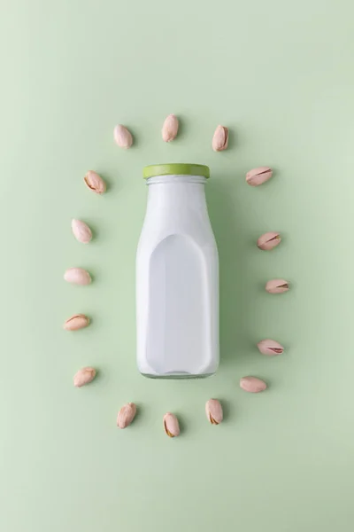 Φιστίκι Γάλακτος Στο Μπουκάλι Που Περιβάλλεται Από Φιστίκια Στο Πράσινο — Φωτογραφία Αρχείου