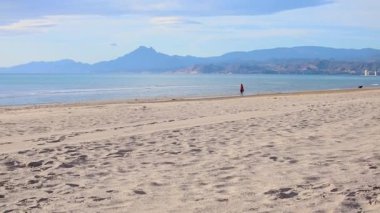 İnsanlar sahilde koşuyor, ağır çekimde.