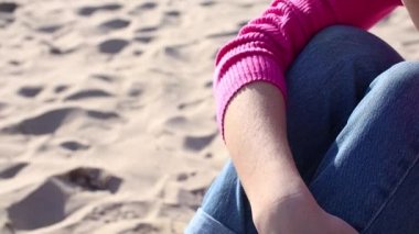 Genç bir kadın kumda sigara içiyor.