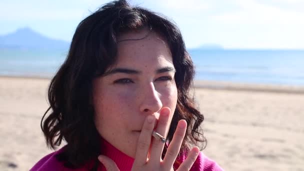 Junge Frau raucht am Strand eine Zigarette aus nächster Nähe — Stockvideo