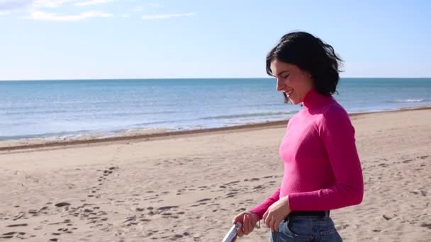 Młoda kobieta robi zdjęcia za pomocą przenośnej kamery na plaży — Wideo stockowe