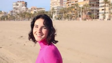 Giyinik genç bir kadın kıyı şeridinde dönüyor, ağır çekimde.