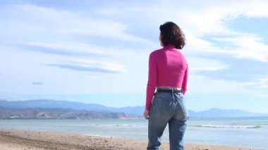 Giyinik genç bayan, dağ sırtındaki sahil şeridine doğru gidiyor.